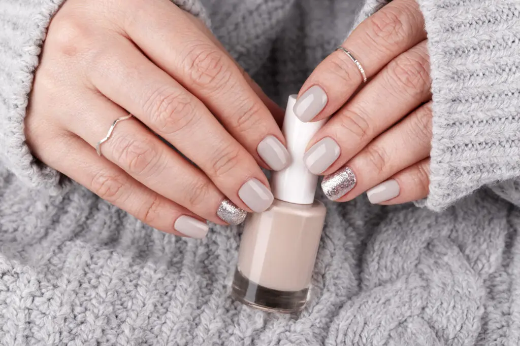 Un par de manos de mujer con la manicure hecha mostrando un esmalte de uñas.