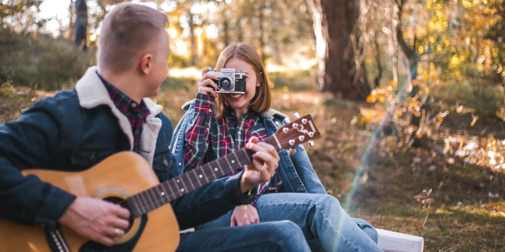 Mujer tomando foto a su cita que toca guitarra