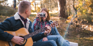 Mujer tomando foto a su cita que toca guitarra