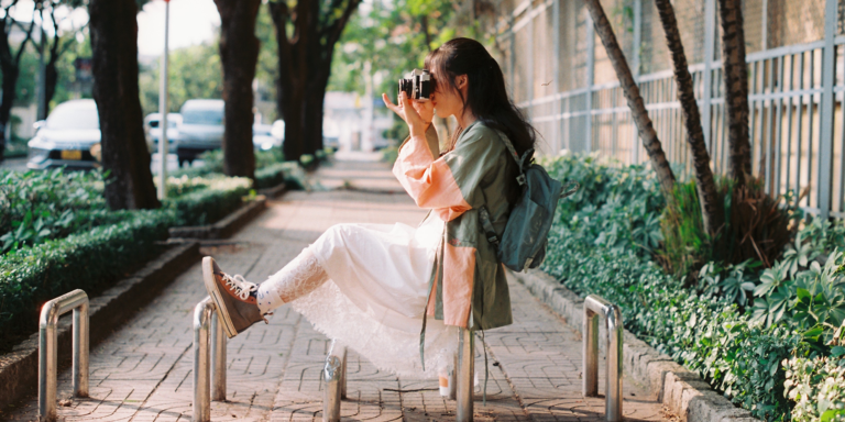 Una joven de perfil apuntando con una cámara para tomar una fotografía