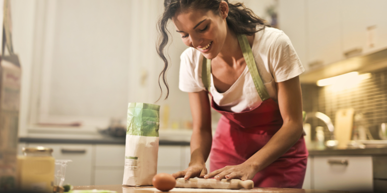 Joven mujer amasa en su cocina